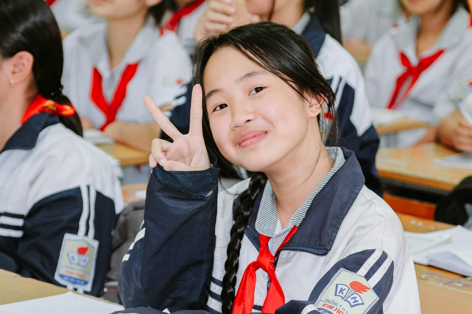 smiling student in classroom making peace sign